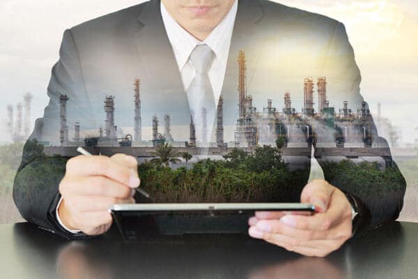 Closeup of a forensic engineer holding a tablet with an image of a power plant overlaid on top