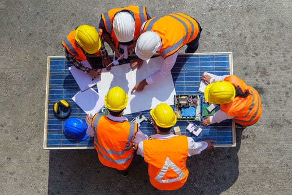 Six engineers gathered around a solar panel